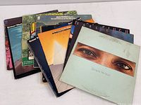 Twelve vinyl LP albums stacked and fanned out, displaying various album covers including Earl Klugh, Smokey Robinson, and others.