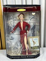 Full view of Barbie Marilyn Monroe doll in original box with vintage background and included mini poster.
