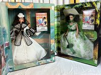 Two Barbie Scarlet O'Hara dolls in original boxes, one in cream and black gown, one in green and white dress with hats, visible aging on boxes