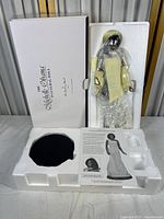 Michelle Obama porcelain collector doll wrapped in plastic inside molded styrofoam packaging with card and accessories space in original white box.