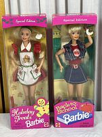 Photo showing both Holiday Treats Barbie and Back to School Barbie dolls in original packaging with pink Special Edition branding. Boxes show aging and wear.