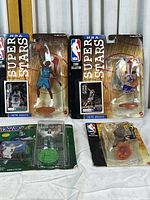 Six NBA Starting Lineup and Mattel Court Collection action figures from the 1998/99 season in original packaging. Figures include those with jersey numbers 41, 8, and 10 in various team uniforms. Packaging shows crease damage and wear.