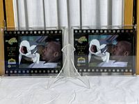 Two professionally framed Space Jam film celcards displayed side by side on a clear stand showing the full front view.
