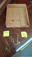 Photo showing all jewelry items laid out in a cardboard box and on table with handwritten post-it notes showing .925 and 14K markings.