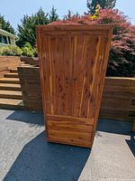 Front view of cedar wardrobe cabinet showing two vertical doors with wood grain and knots.