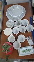 Top view of the full lot showing Crestwood plates, bowl, sugar bowl, 7 floral design cups, cream and sugar dispensers, strawberry shaped teapot, and Pyrex butter dish.