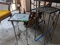 Two metal plant stands, one with stained glass style top, other with embossed metal top.