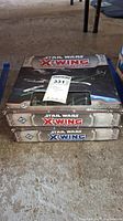 Three Star Wars X-Wing Miniatures Game boxed sets stacked, showing game logos and artwork on covers.