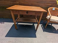 Full view of wooden table with single drawer and lower shelf, showing overall shape and condition.