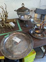 Full set of silver-tone serving pieces including tray, pedestal dishes, gravy boat with tray, and chafing dish on table.