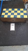 Closed view of the wooden chess box featuring a blue and natural wood checkerboard top.