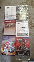 Photo showing six war-themed board games in shrink wrap or sleeves including Roma II, Queen of the Oil, Battle for Kursk, Strike the Bear, SAC, and another