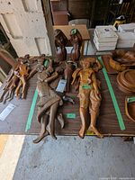 Photo showing two sets of wooden dancing figures lying on a table alongside wooden bowls, nuts, and tags with lot numbers.