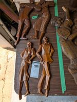 Five vintage wooden carved dancing figures arranged on a wooden surface, showing their full bodies and carved details.