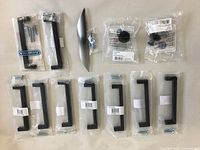 Full lot of 12 cabinet hardware pulls and knobs laid out on white surface showing all items in packaging and loose.