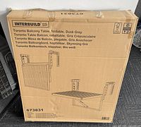 Photo of the product packaging showing product name, model 673831, and foldable balcony table illustration in dusk grey.