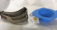 KONG Ultra durable padded dog collar with handle in tan, next to blue collapsible silicone pet bowl with tag.