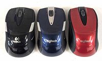Top view of three Logitech M525 wireless mice in black, blue, and red, showing scroll wheels and logos.