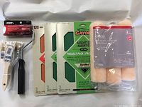 Photo showing 3 paint rollers, 1 small refill roller with handle, 3 packs of Gator sandpaper.