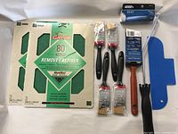 Photo showing the 2 packs of Gator 80 grit sandpaper sheets alongside the brushes, roller, and trim guide.