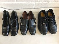 Three pairs of black leather shoes lined up: Camila Casas heels, Lottuse buckle shoes, and Tarantula work boots.