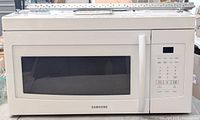 Front view of the white Samsung over the range microwave showing large front window and the right side digital touch control panel with buttons and display.