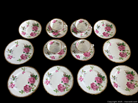 Top-down photo showing all tea cups, saucers, coffee cup saucers, and dessert plates arranged to display their floral pattern and gold trim.