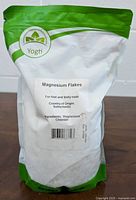 Front of resealable white and green pouch labeled Yogti Magnesium Flakes for foot and body soak with product details including ingredients magnesium chloride and country of origin Netherlands.