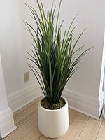 Full view of artificial tall green grass plant in white cylindrical pot showing overall size and structure.
