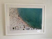 Full view of the framed beach photo hung on a wall showing the entire print and frame