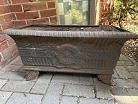 Front view showing central wreath relief, fluted panels, scalloped rim, and scrolled feet