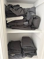 Shelves filled with folded grey bedding including sheets, pillow cases and duvet covers.