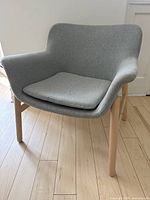 Front angled view of IKEA Vedbo armchair showing light grey upholstery, wooden legs, and removable cushion.