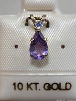 Front view showing pear-shaped purple amethyst in 10K gold setting with smaller round gemstone above