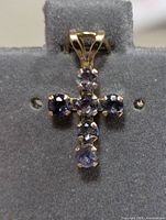 Close-up front view of the 10K gold cross pendant set with six round sapphires.