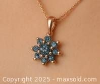 Full view of the pendant necklace worn showing the flower-shaped cluster design with blue lab diamonds and 14k gold chain.