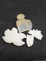 Four genuine carved opal pieces shown on black background: a bird, a fan shape, and two smaller carved pieces.