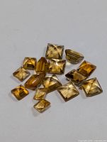 Multiple loose genuine citrine gemstones of varying cuts and sizes, arranged on a white background.