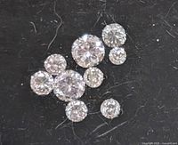 Close-up of 10 loose round cut diamonds on a black background showing clarity and brilliance.