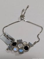 Photo showing the full adjustable silver bracelet with multi gemstone central setting and sliding clasp adjustment mechanism.