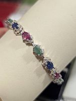 Bracelet draped over a white display stand showing alternating colored gemstones.