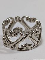 Close-up of the silver openwork heart patterned ring showing intricate design and polished finish.