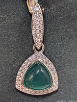 Front view of silver pendant featuring a triangular green onyx cabochon with cubic zirconia stones around and on the bail.
