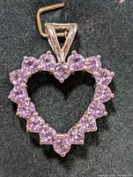 Front view of silver heart-shaped pendant with amethyst stones set around it, showing overall shape and sparkle.