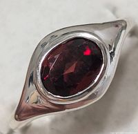 Close-up of the garnet stone set in polished sterling silver with pointed ends of the band visible.
