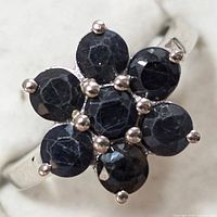 Close-up view of the sterling silver ring with seven round faceted sapphires arranged in a flower cluster.