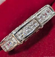 Close-up angled view of the silver CZ ring on red background showing the stones and setting detail.