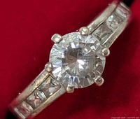 Close-up of the round-cut CZ stone set in six-prong sterling silver ring with princess-cut CZ stones on the band.