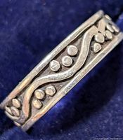 Close-up photo showing the side view of the silver ring with raised dots and wave pattern detail.