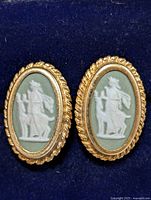 Front view of silver cameo earrings showing oval white classical figure on green background with gold-toned rope border.